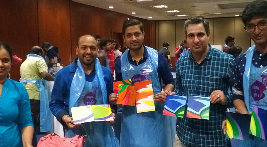 TINKR participants holding colourful paintings from a Paintastic session